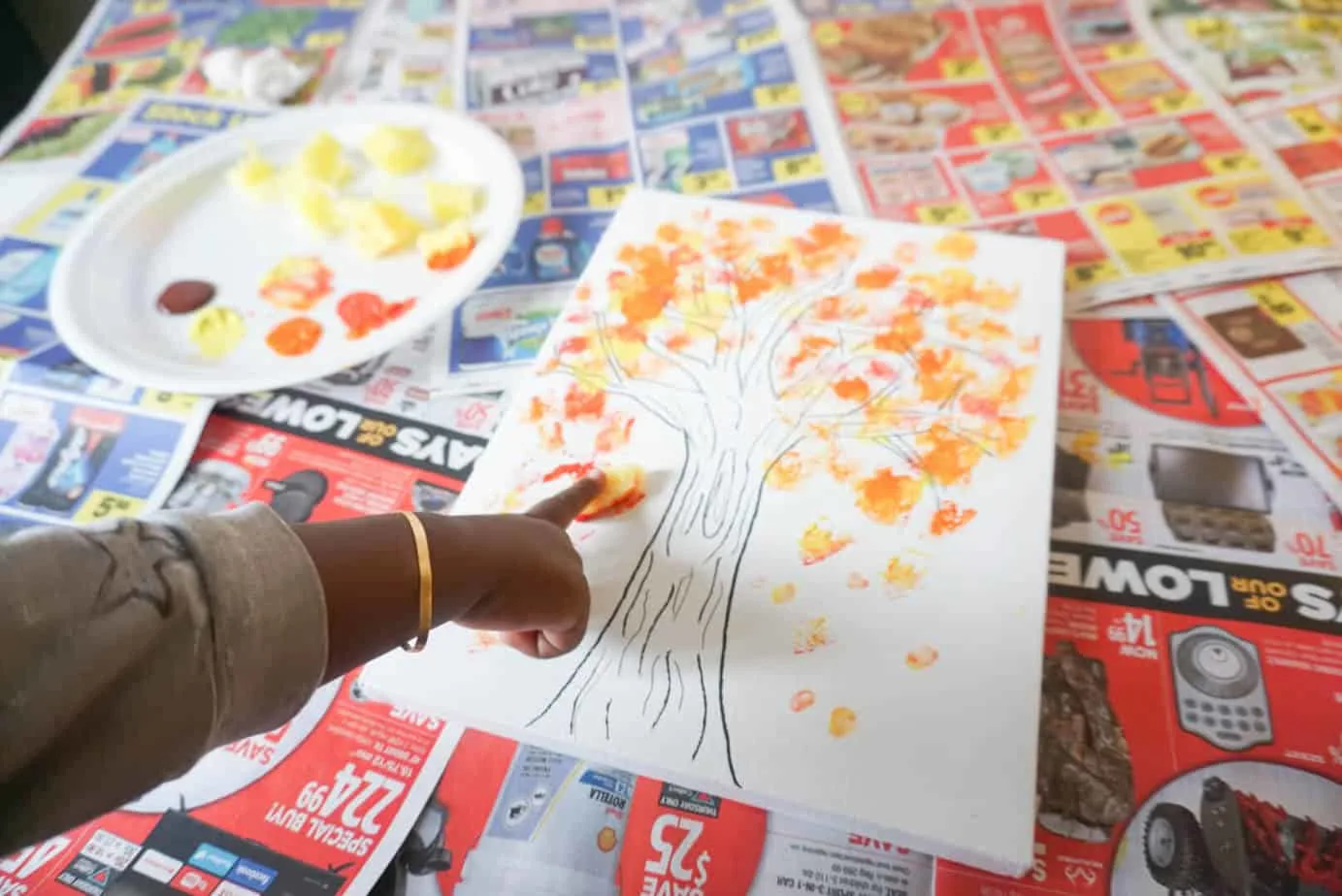 toddler finger painting a fall tree with colorful leaves