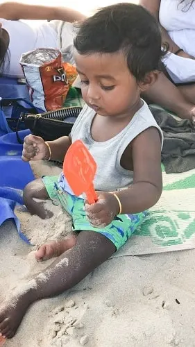 baby playing with beach toys at the beach in sand