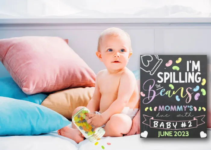 baby boy spilling jellybeans next to pregnancy announcement sign that says 'I'm spilling the beans. mommy is due with baby #2'