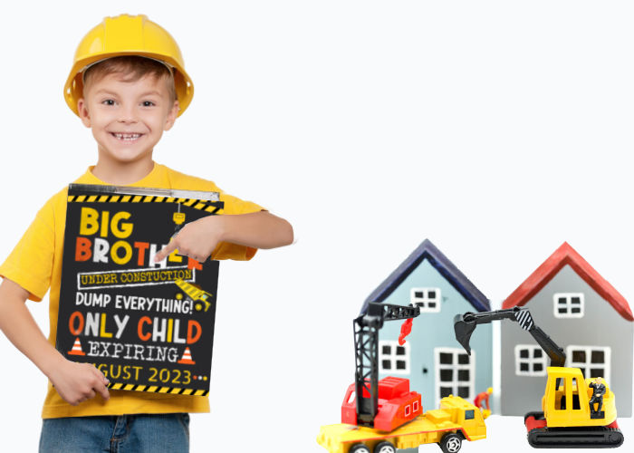 toddler boy wearing hard hat and holding under construction baby announcement sign
