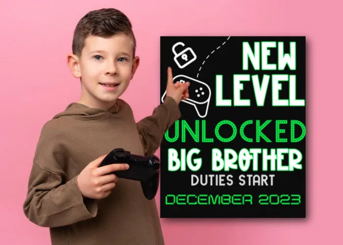little boy holding video game controller and pointing to big brother pregnancy announcement sign