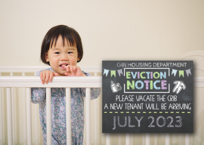little Asian toddler in crib next to eviction notice pregnancy announcement sign