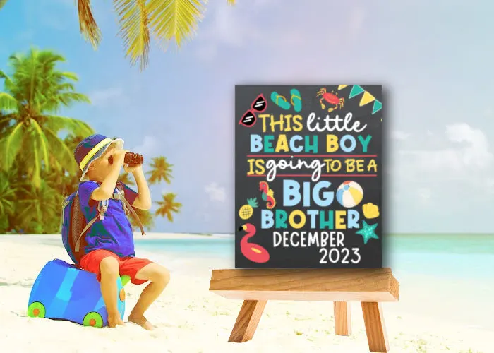 little boy at the beach sitting next to beach big brother announcement board