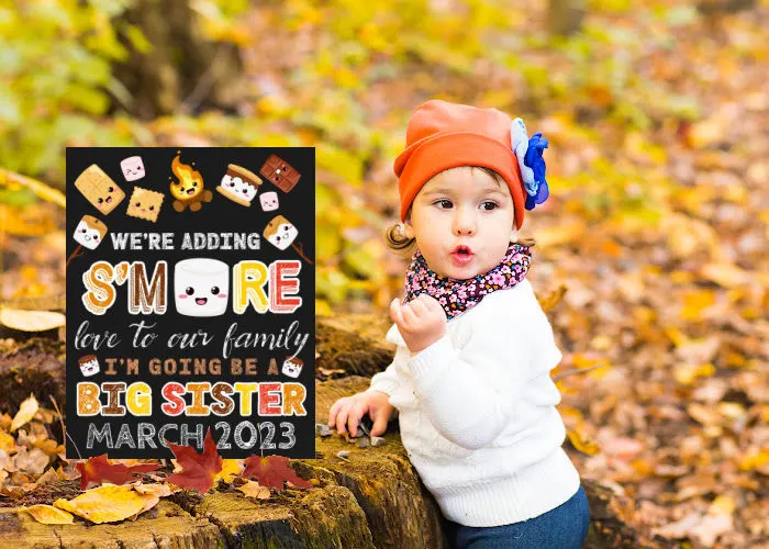 baby girl outside on fall day standing next fall themed big sister announcement s'more love