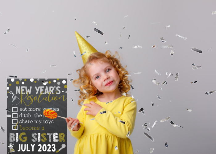 little girl wearing party hat and pointing to new years big sister pregnancy announcement sign