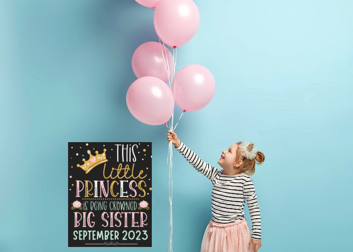 little girl holding balloons and wearing crown next to princess themed big sister announcement sign