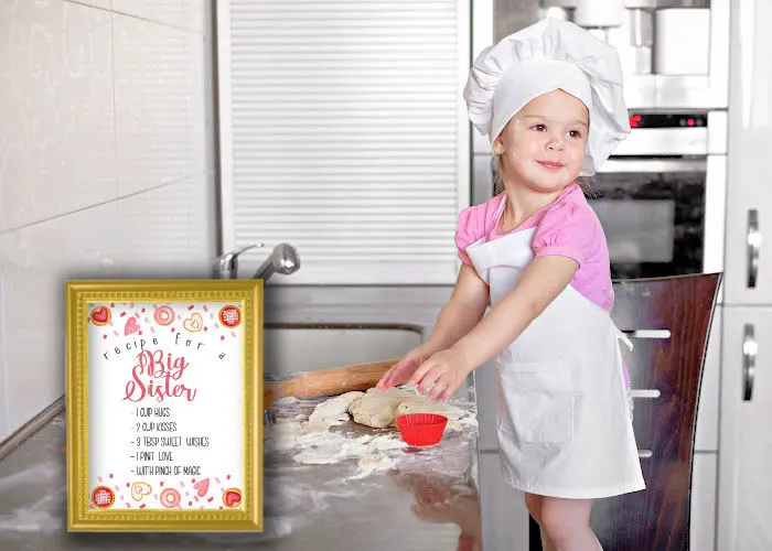 little girl in apron and chef hat baking next to recipe for a big sister announcement board