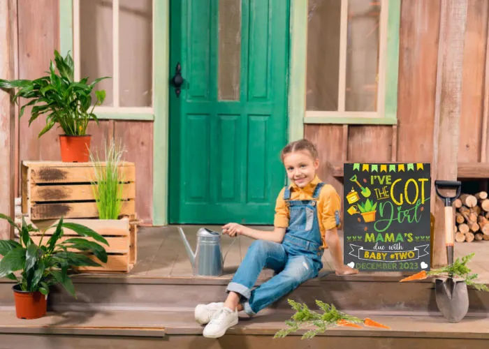 little girl with watering can sitting next to spring gardening themed big sister pregnancy announcement sign