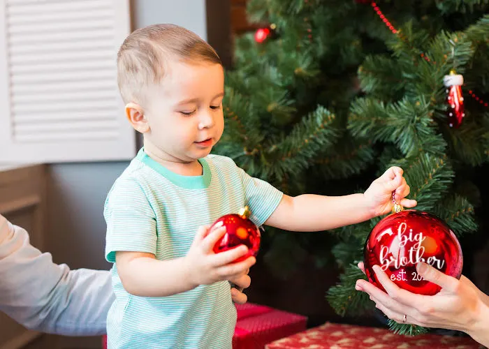 little boy holding Christmas pregnancy announcement ornament big brother est.