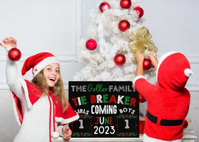 brother and sister dressed in Christmas costumes decorating tree and standing with a Christmas pregnancy announcement for third pregnancy tie breaker baby reveal sign