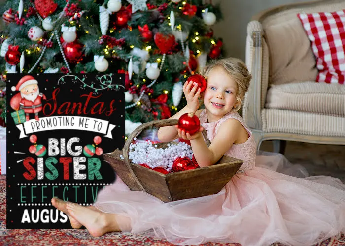 little girl sitting next to Christmas tree holding ornaments next to Santa is promoting me to big sister sign