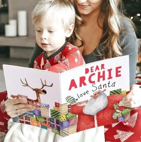 little boy reading personalized Christmas book with his name on it