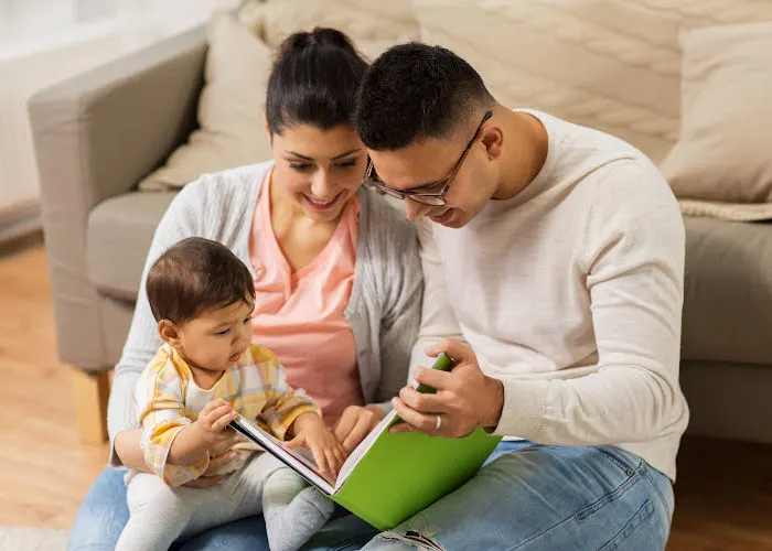 mom, dad, and baby sitting on the floor reading a Christmas board book together