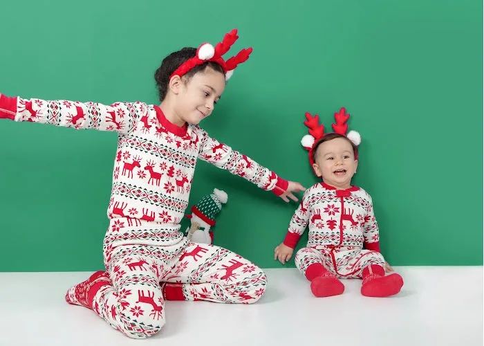 little girl and baby brother dressed up in matching Christmas pajamas