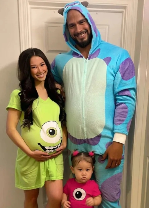 pregnant family costume idea: monster's inc. mom is dressed as mike wazowski. dad is sully and theri baby is dressed as boo.