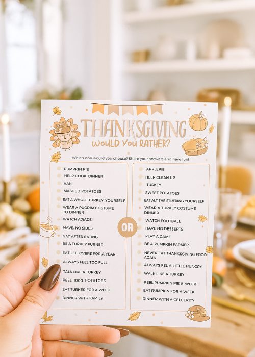 woman's hand is holding up Thanksgiving would you rather game printable