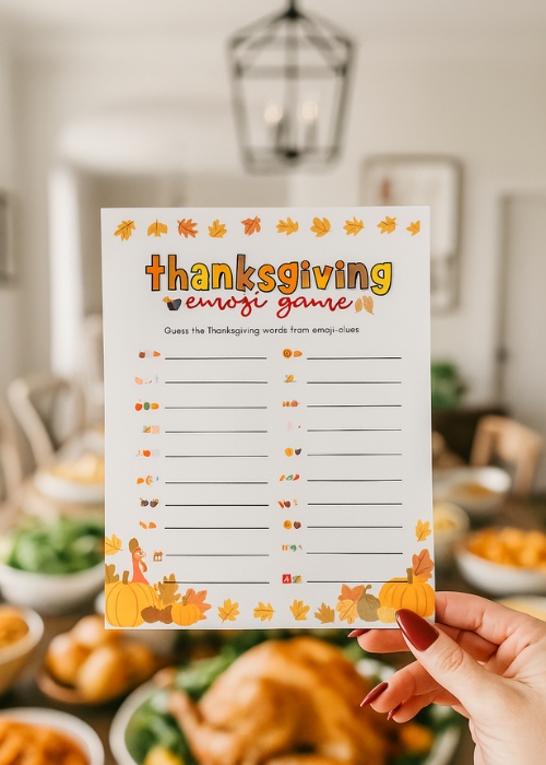 a hand is holding up the Thanksgiving party game   emoji pictionary at the thanksgiving dinner table