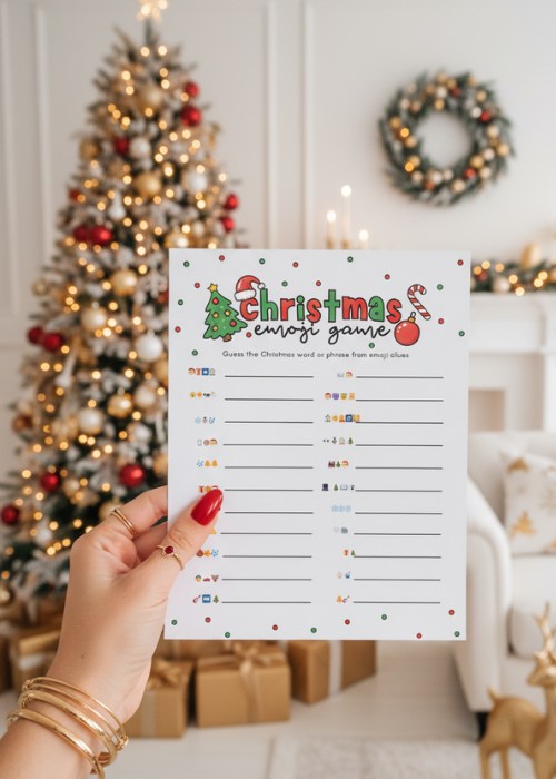 a woman's hand is holding up the Christmas emoji game in front of the christmas tree